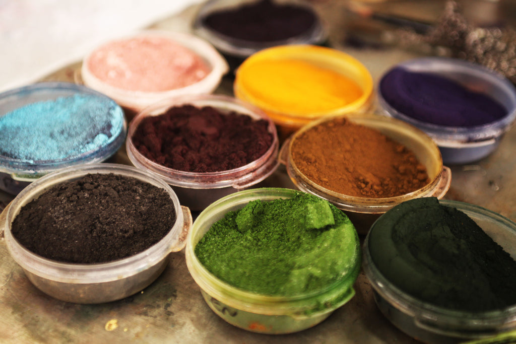 A collection of colourful powder dyes arranged in open tubs